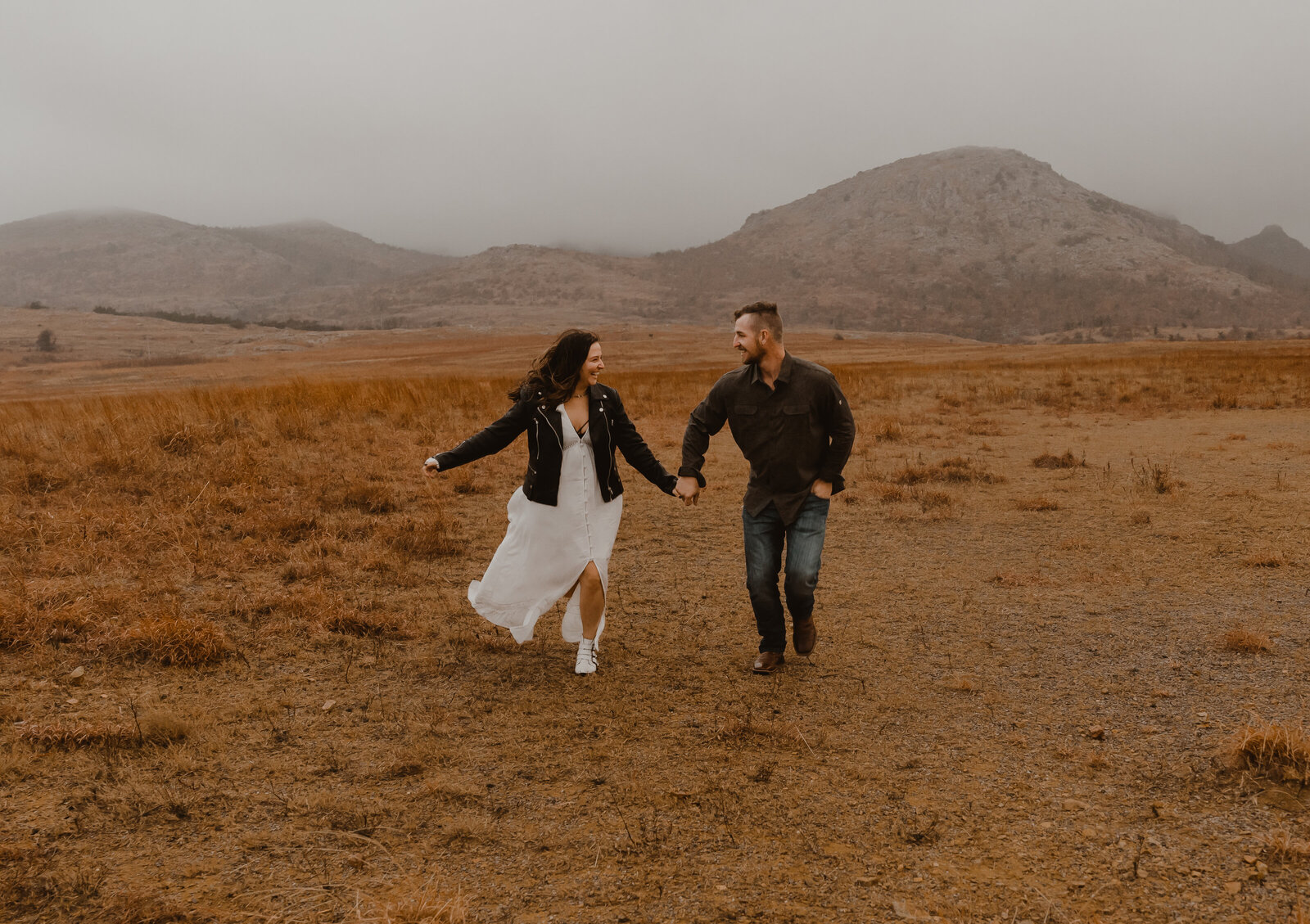A rainy elopement day in the wichita mountains. The couple is running and having fun.