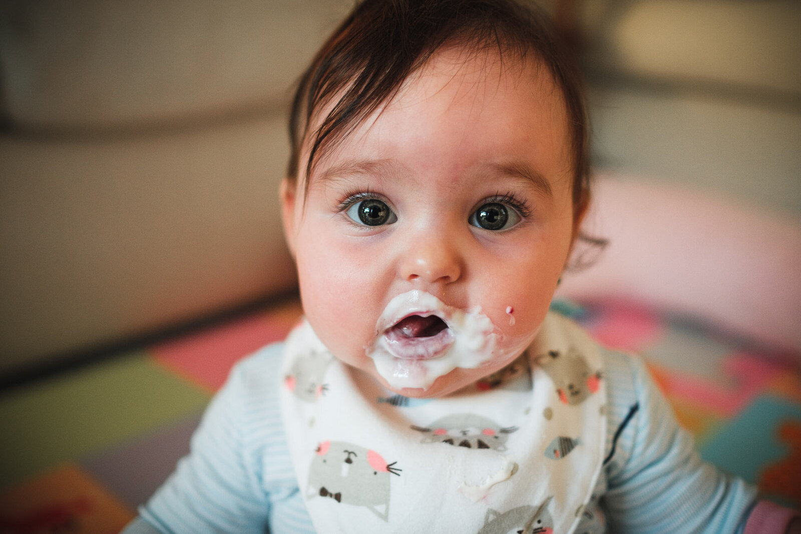 baby looks toward camera covered in yogurt