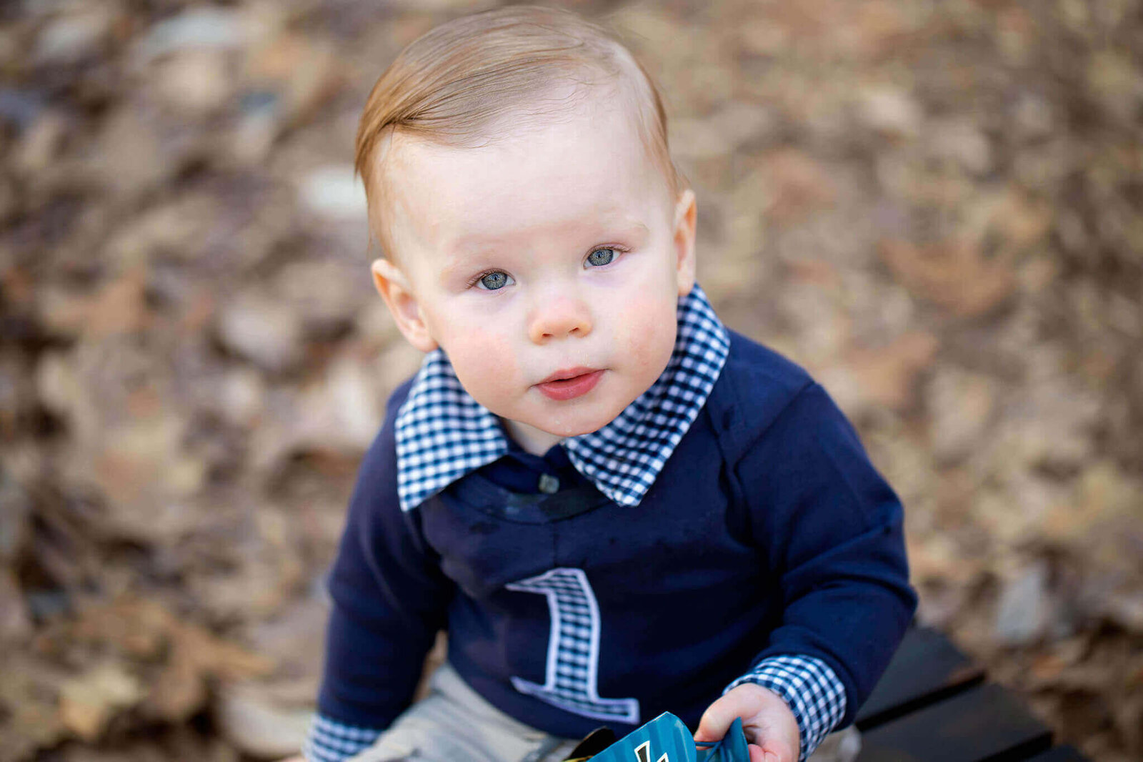 A little boy in a blue sweat and khaki pants celebrating his first birthday.