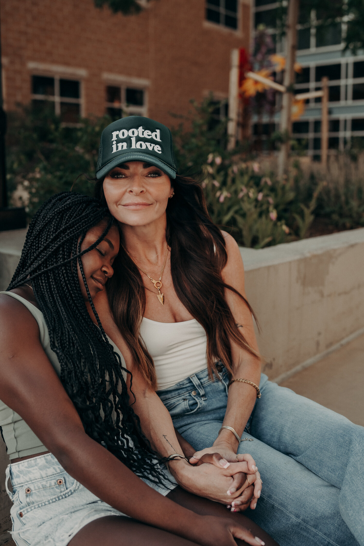 A mother holds her teenage daughter as she makes iContact with the audience, wearing a hat with an inspirational quote on it.