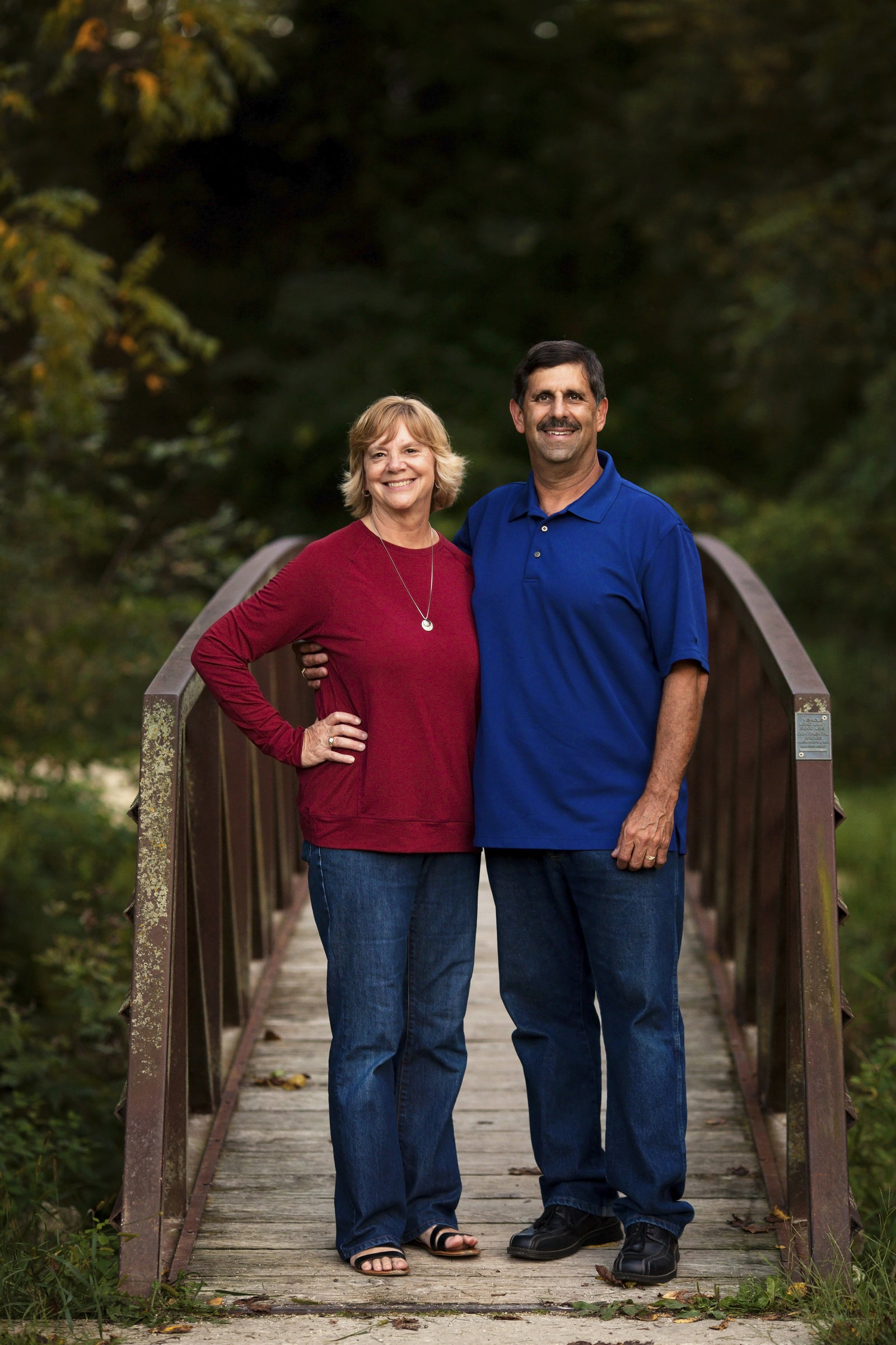 Older couple standing together on bridge, smiling.