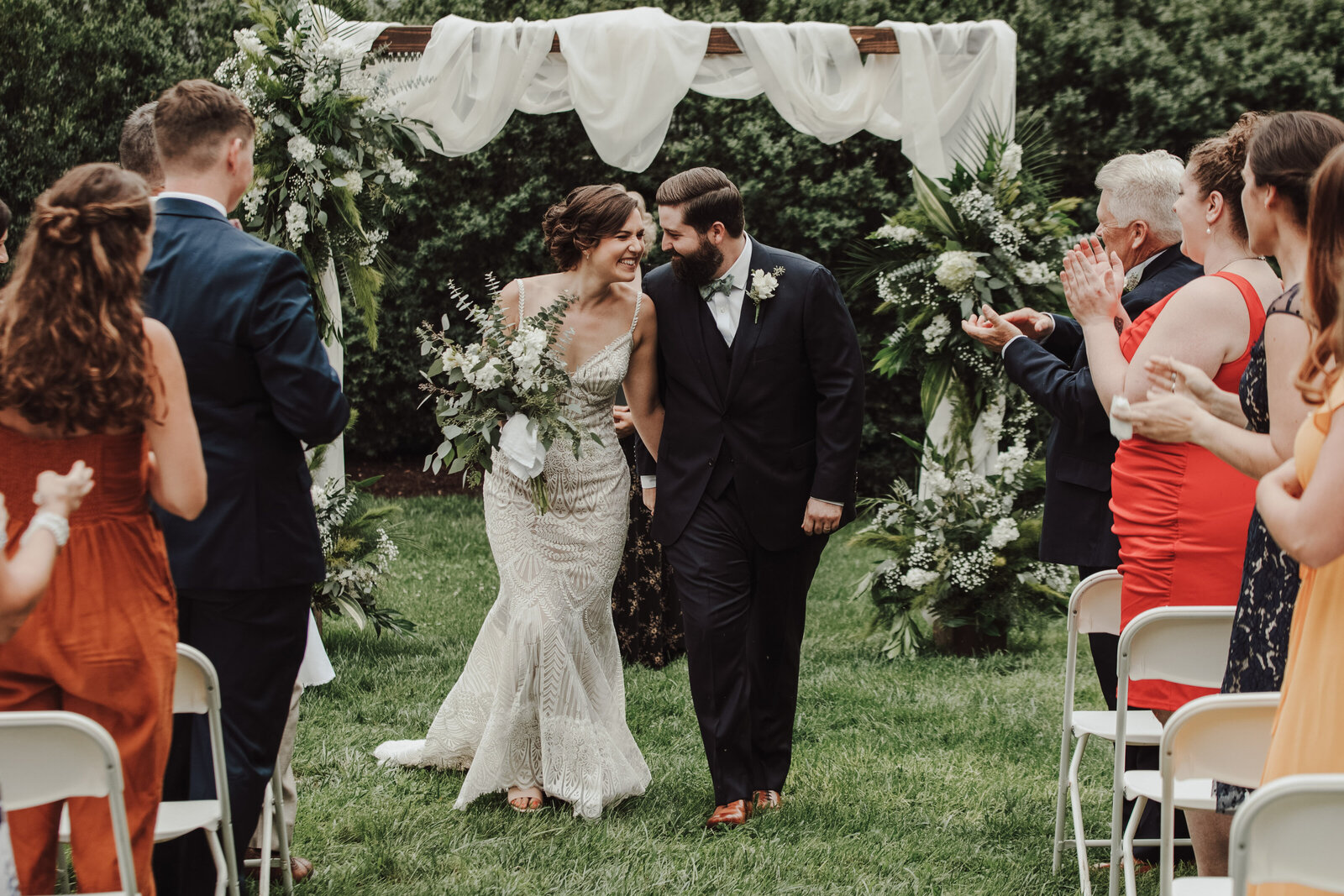 A bride and groom smile and they walk up the aisle