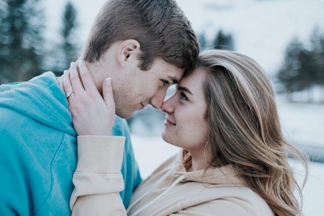winter engagement session with man and woman close together touching their foreheads and noses together as the woman holds the mans neck