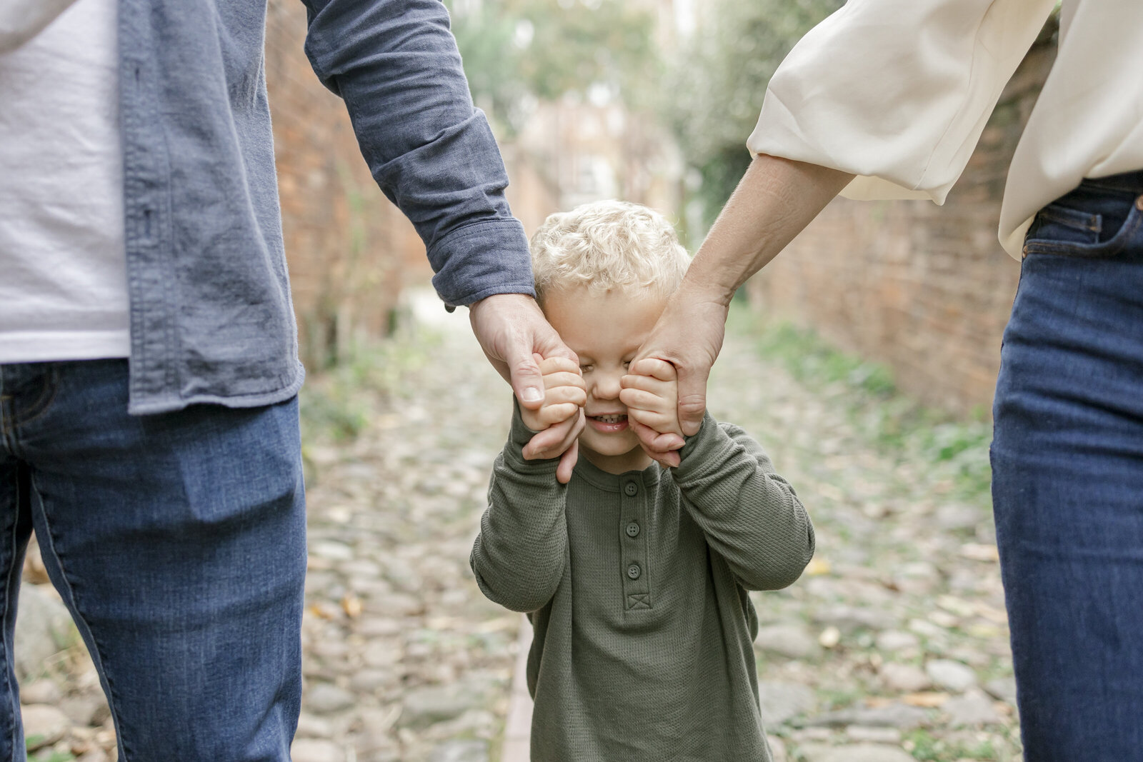 Young boy holding parents hand in front of face