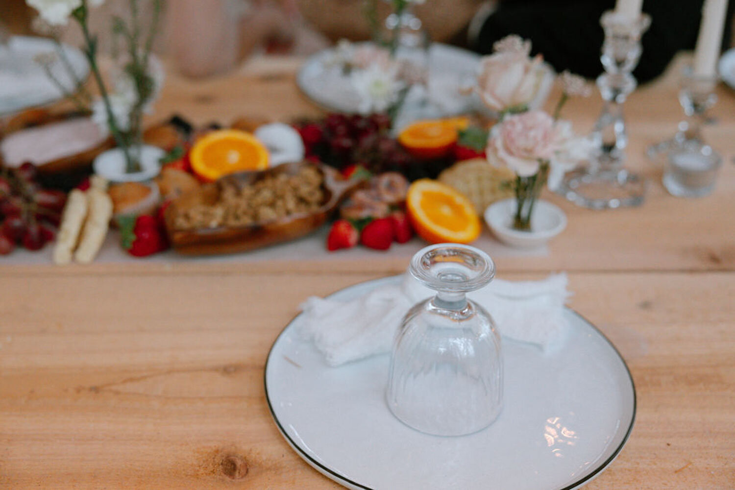 Close-up of table with fruits, cheeses, and a glass upside-down