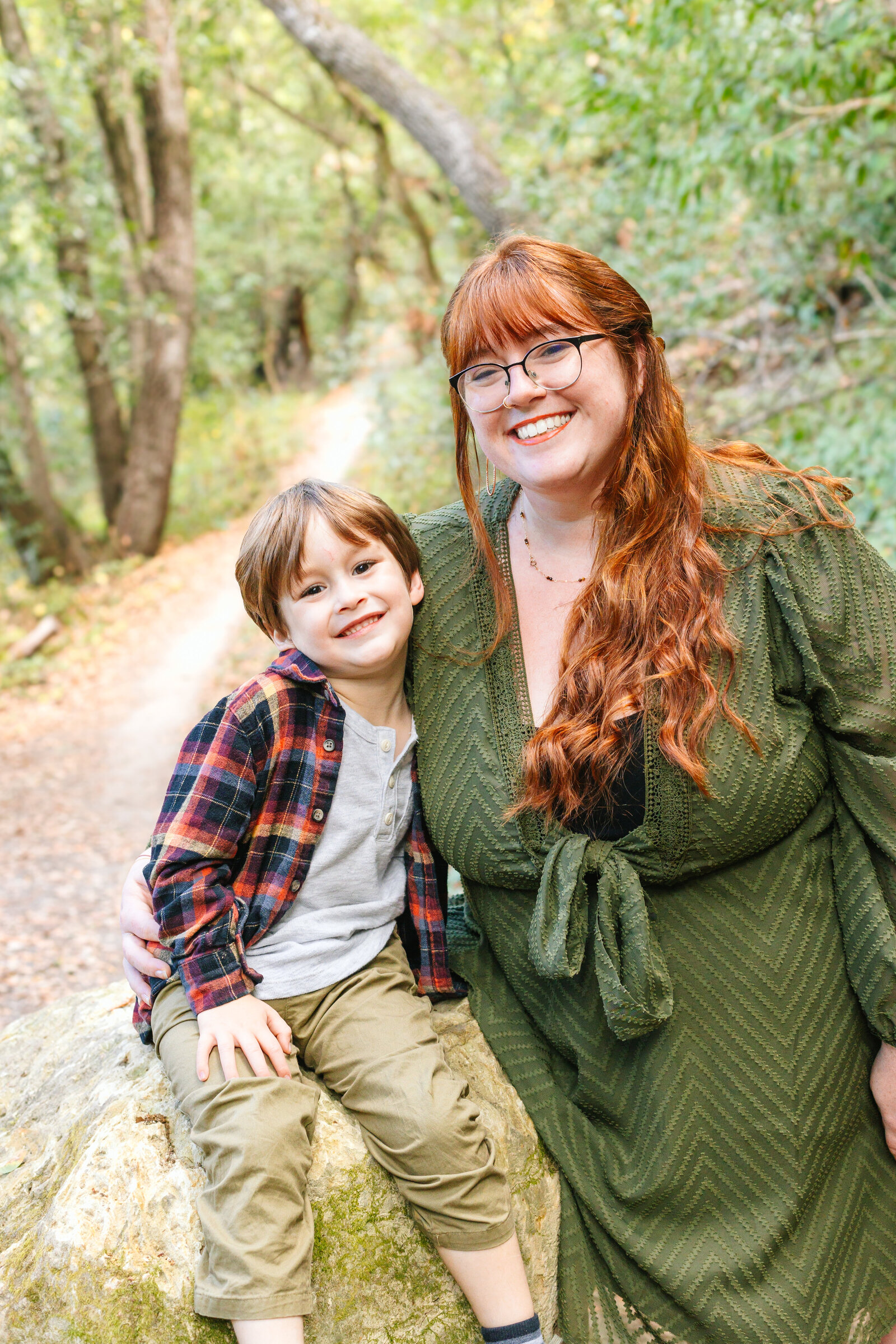 A family of 3 poses for photos in a forest in Santa Cruz, Ca.