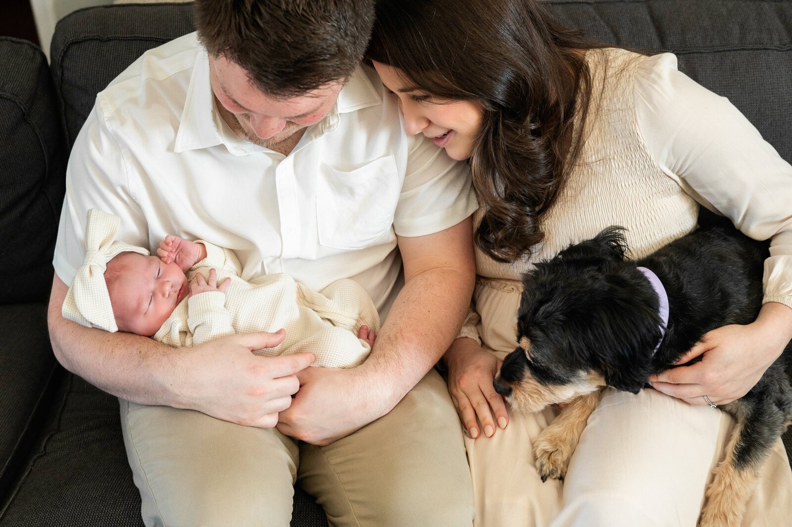 family with a dog looking at newborn girl in dads arms