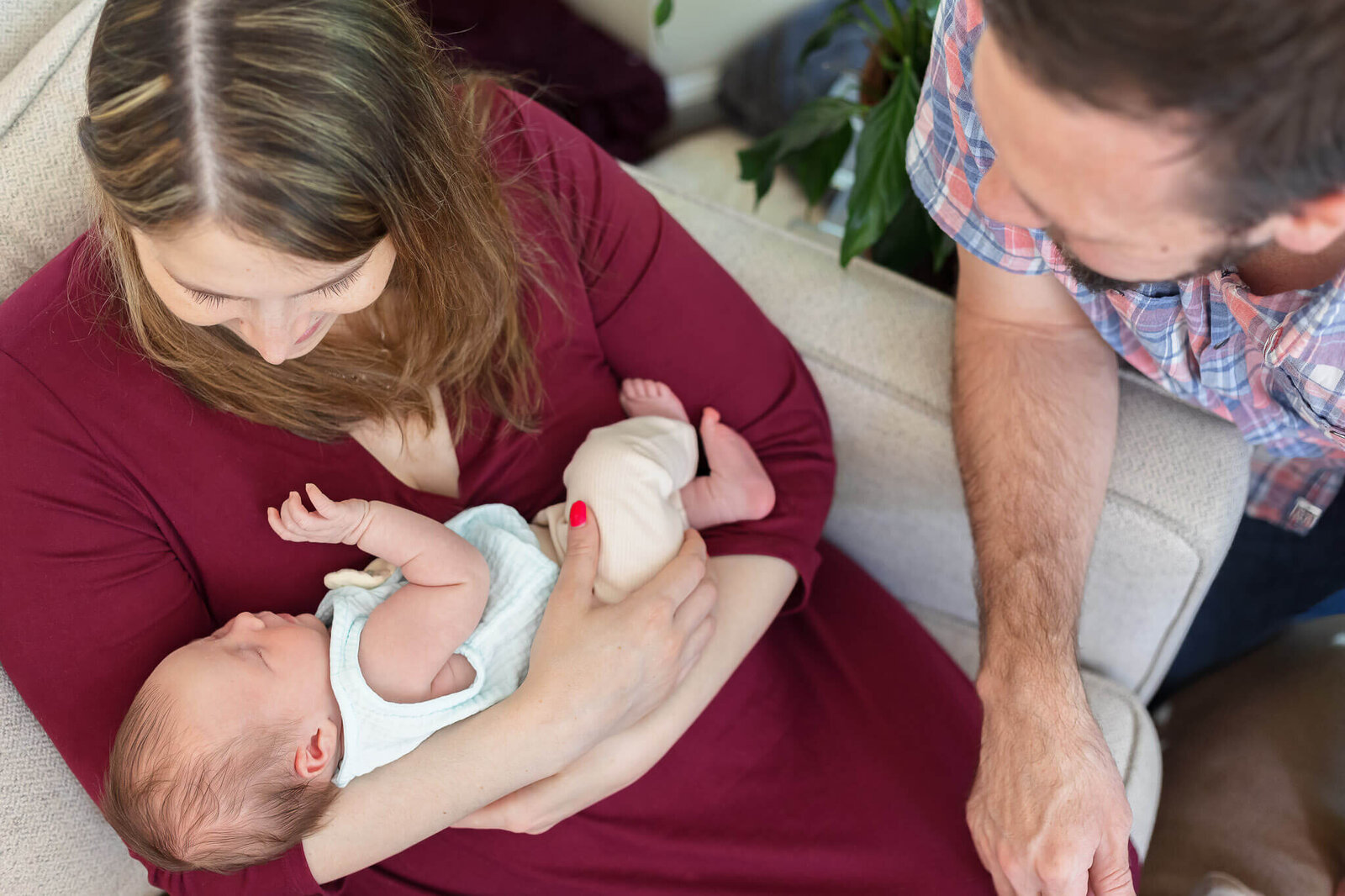 A mom holding her newborn daughter in her arms while dad looks down on them.