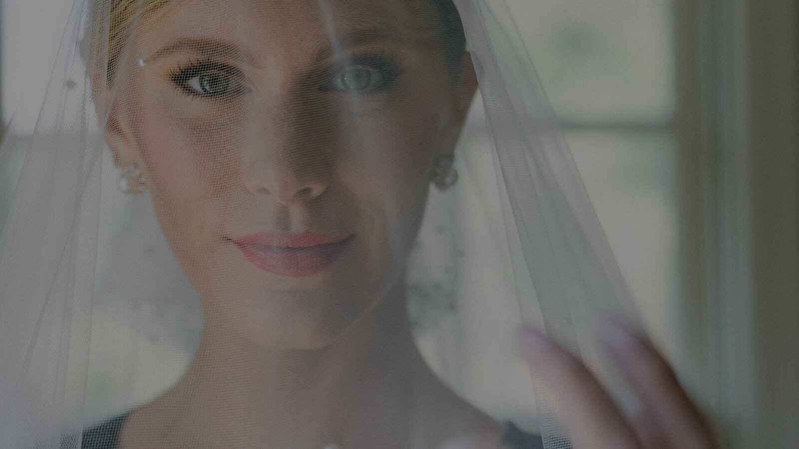 A stunning bride in a veil, captured in a portrait while holding her hand. Perfect for Getting Ready Photo ideas.