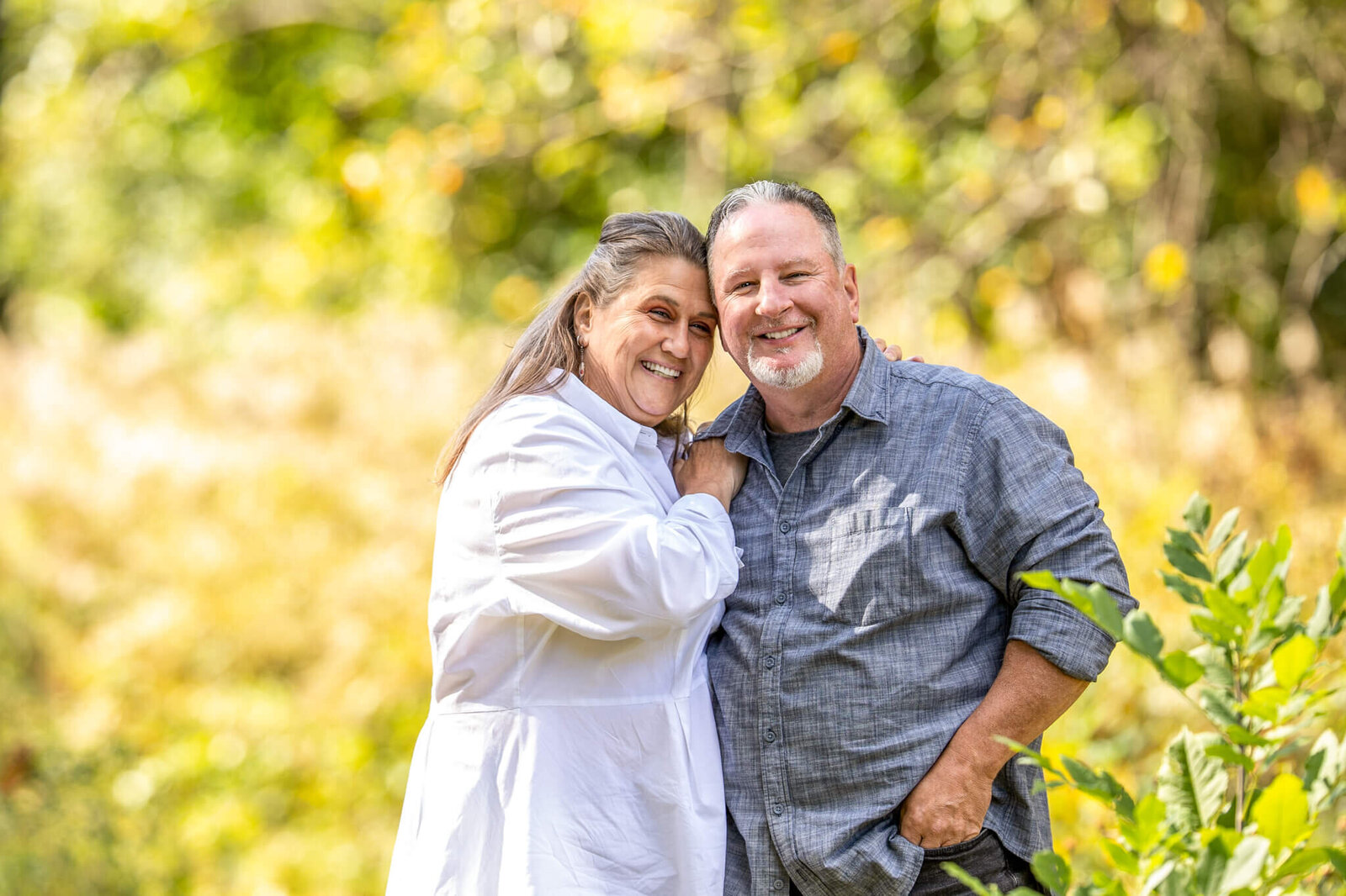 Adult couple of male and female leanign into one another during fall photoshoot smiling