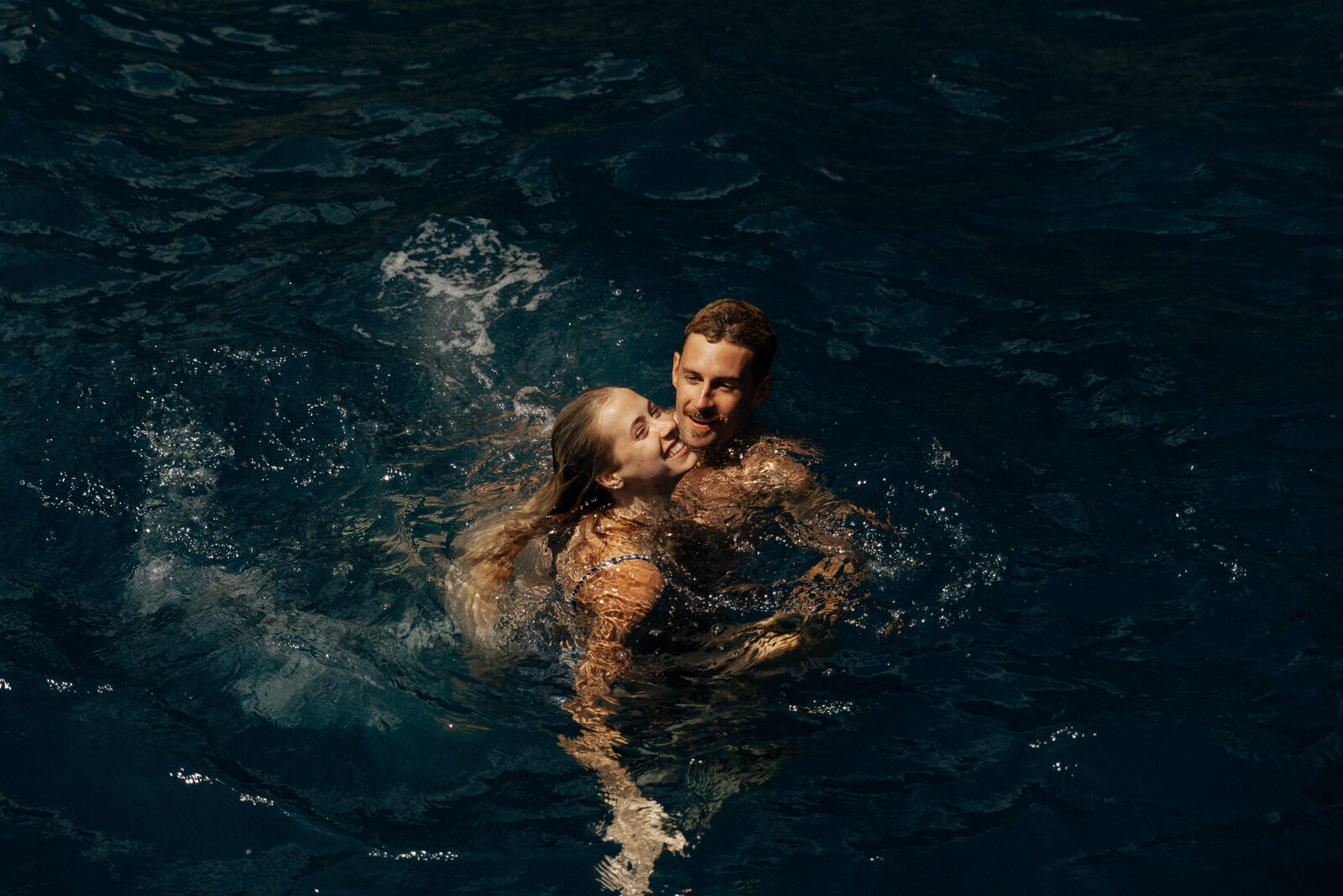 A couple celebrates in the ocean captured by an elopement photographer.