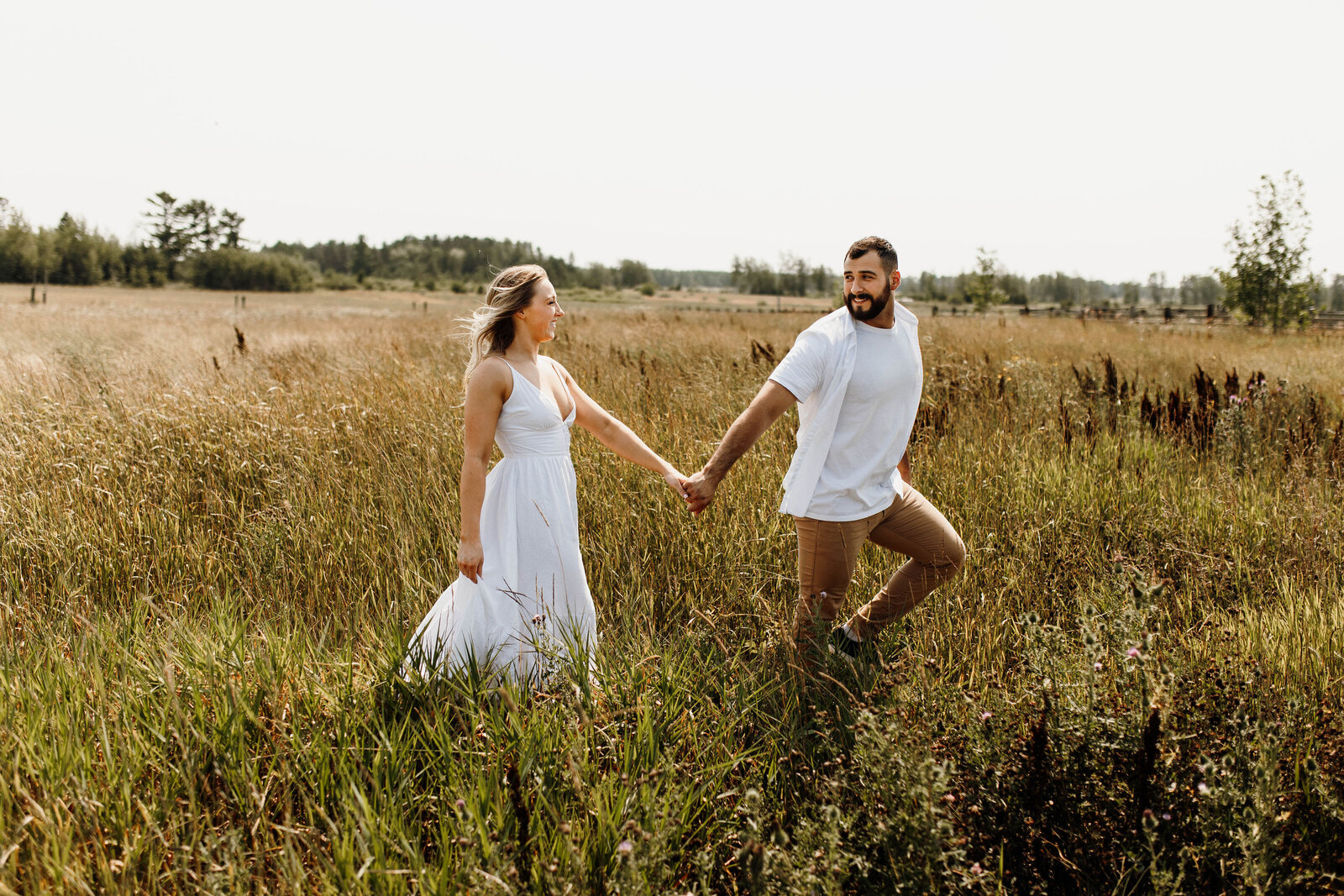 Couple holding hands and walking through a field
