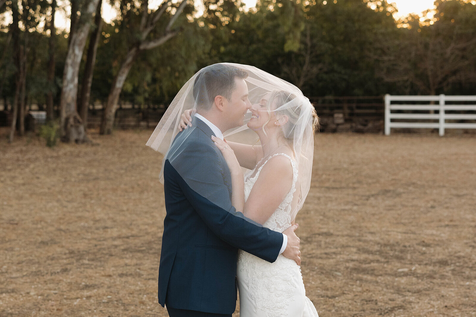 Bride and groom under her veil at golden hour