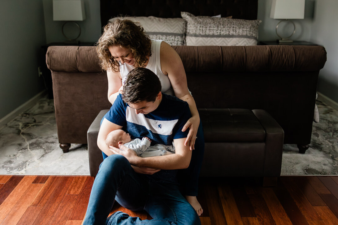 Woman embracing man as they gaze lovingly at newborn baby