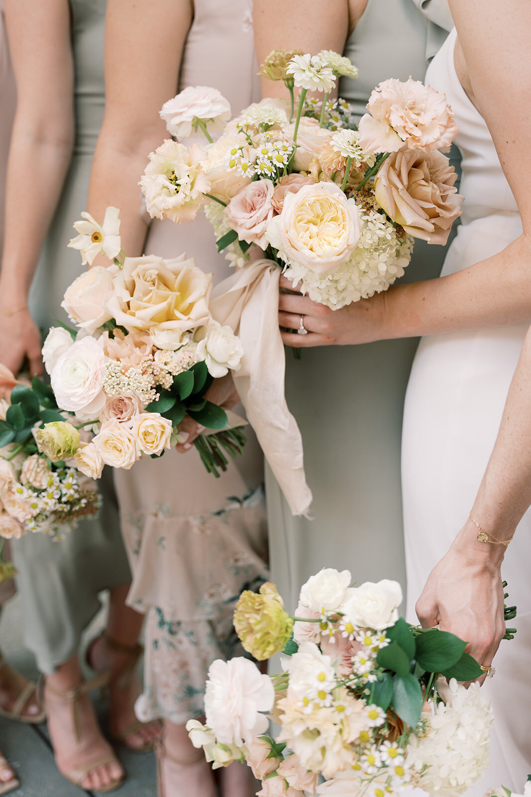 The bridal party holding bouquets with peach and blush garden roses, ranunculus, daisies, white hydrangea, and lisianthus.
