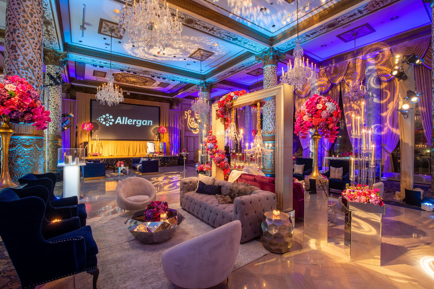 Elegant event lounge setup with chandeliers and vibrant floral decor