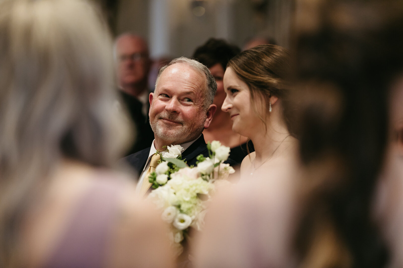 The father of the bride smiles at the bride at the altar