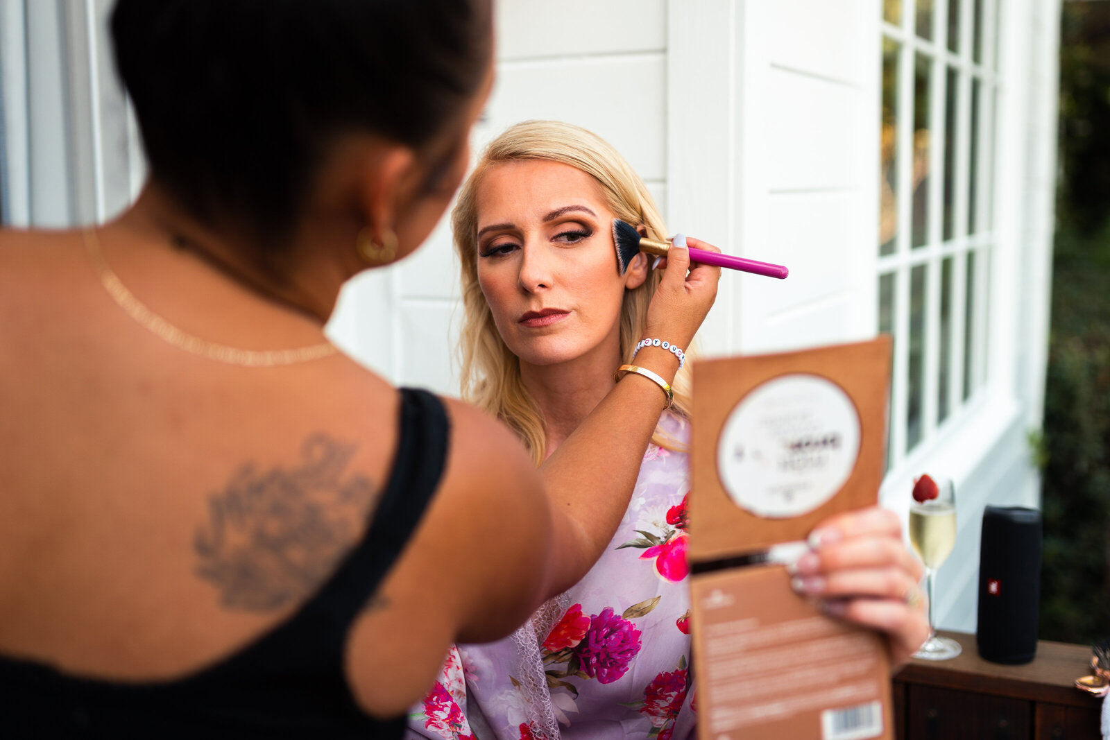 Bride looking into a mirror as she has her make-up done before wedding ceremony.