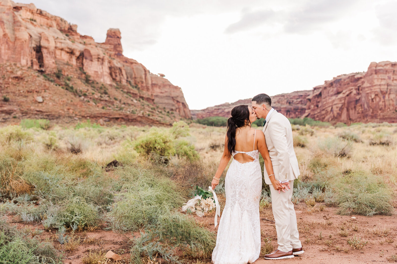 Bride and groom share a kiss in front of the mountains in Moab Utah