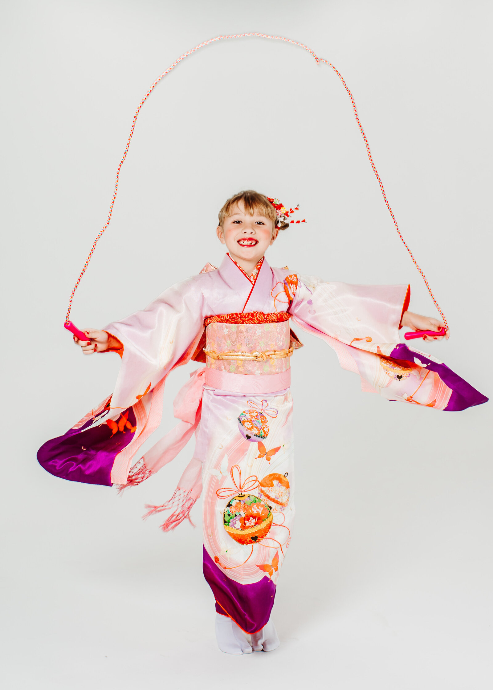Young girl in pink kimono happily jumping rope for Shichi-Go-San celebration | 七五三 ピンクの着物で縄跳びを楽しむ女の子