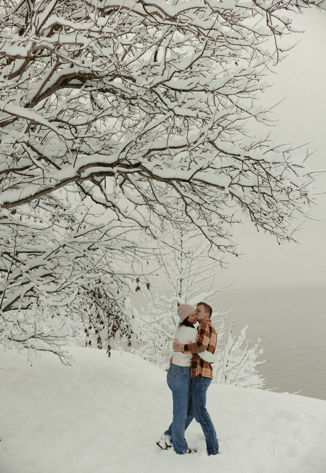 Couple standing under a tree covered in snow