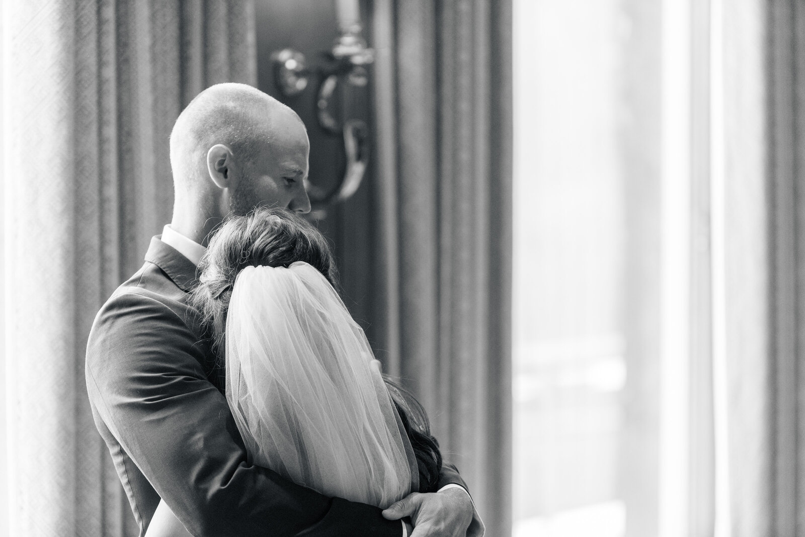 Black and white photo of bride and groom hugging in Sun Room at the Sun Valley Resort at Trail Creek Cabin Wedding taken by the Best Sun Valley Wedding Photographers