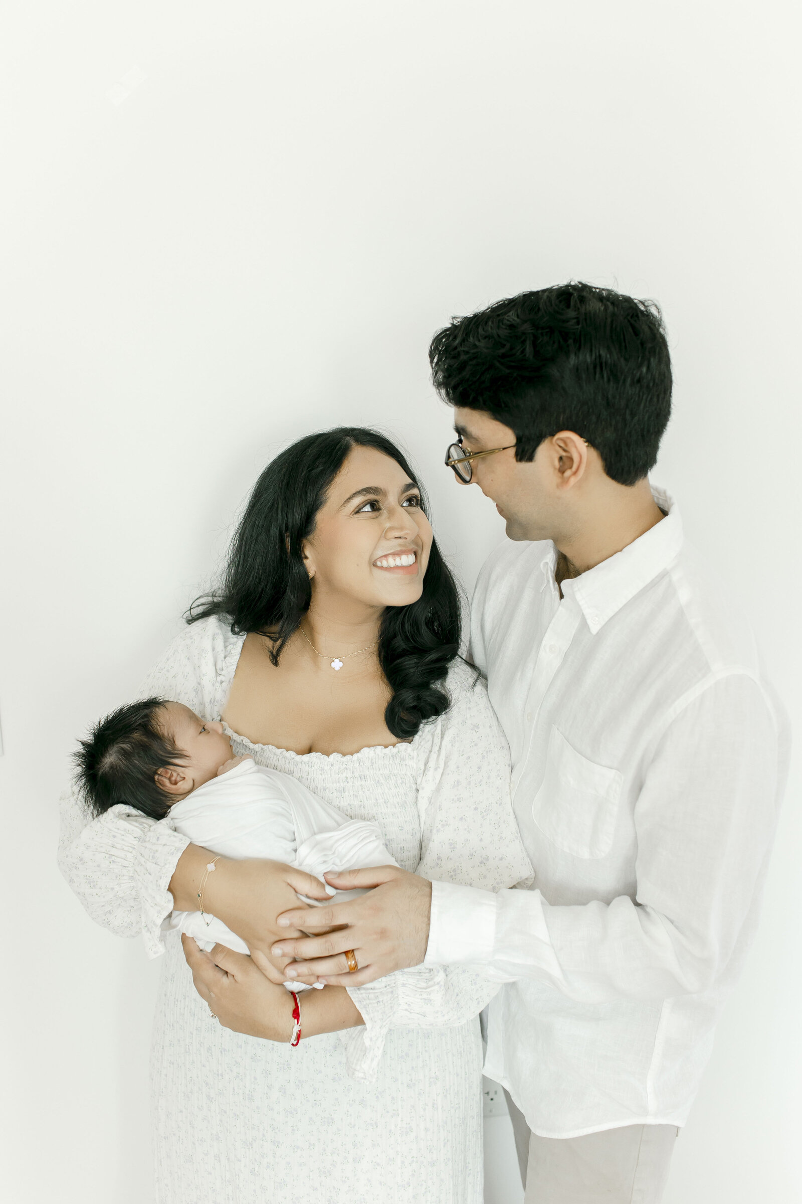 mom smiling at dad holding newborn taken by best nj newborn photographer