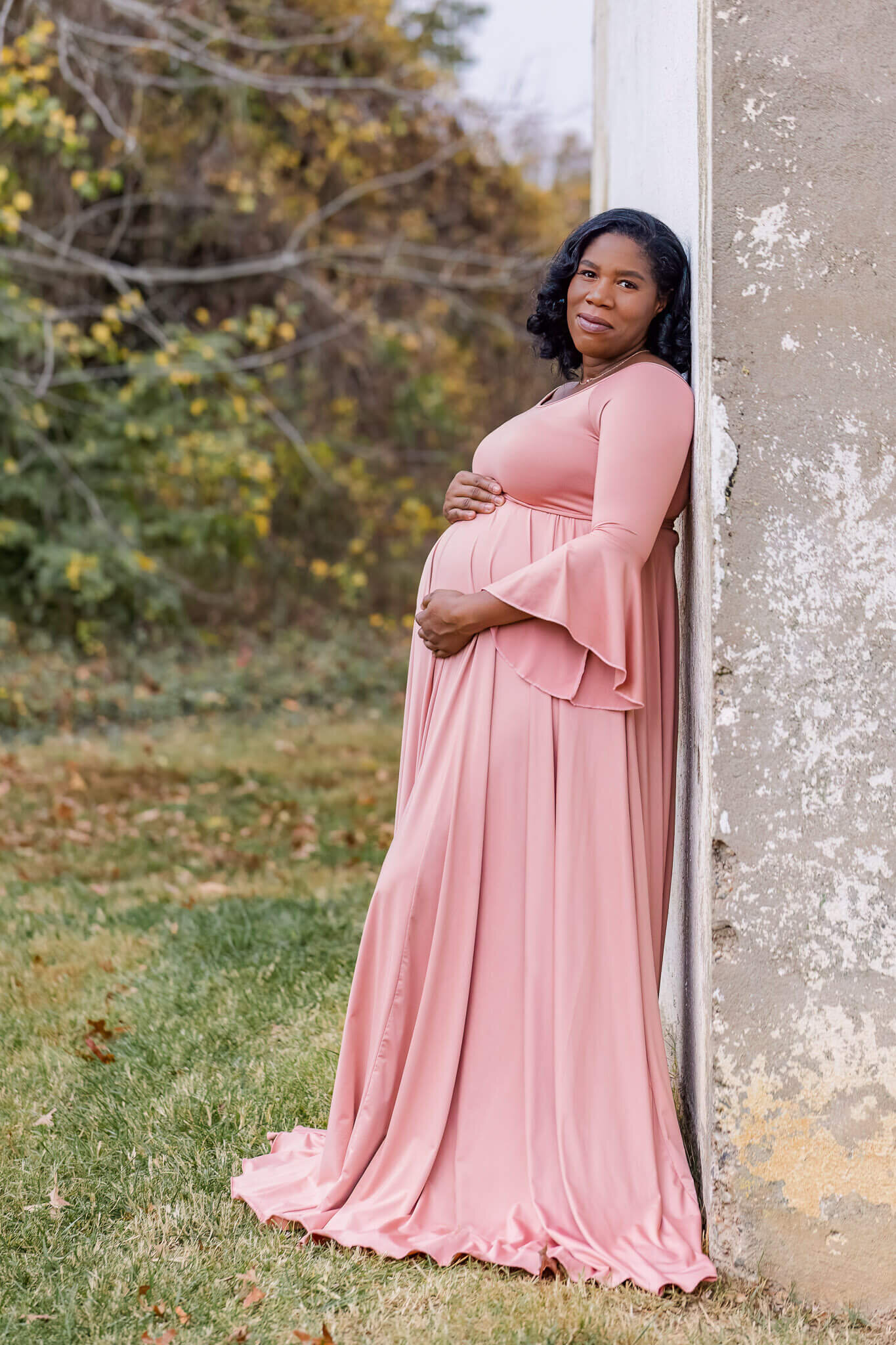 A beautiful mother-to-be leaning against a building during her maternity portraits.