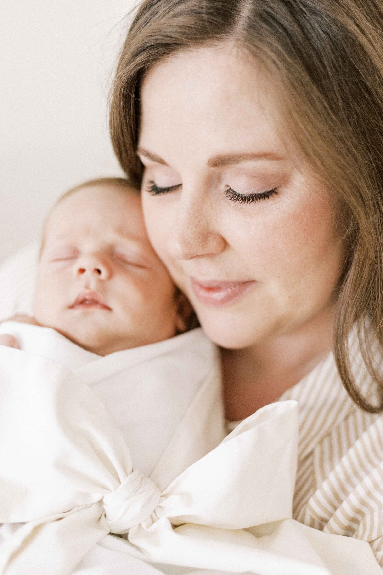 mom holding baby up to her cheek in newborn photos in peoria illinois 