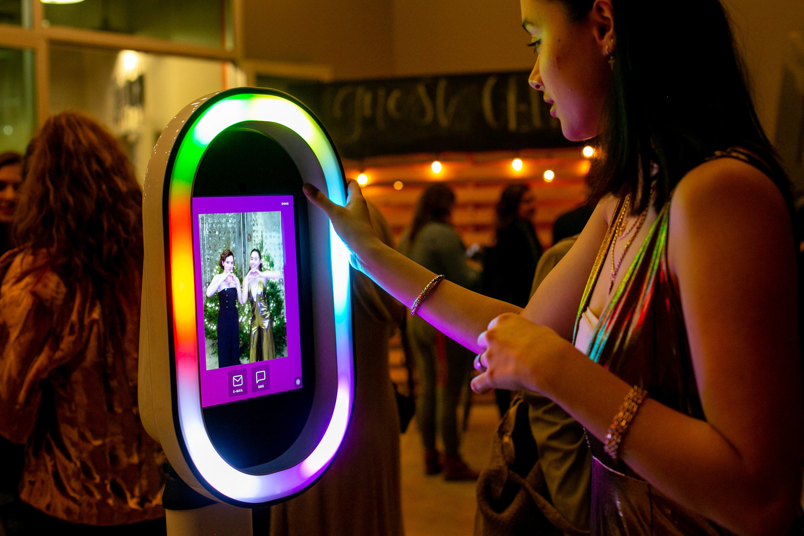 Woman smiling as she texts her photo booth picture to her phone at the end of her session