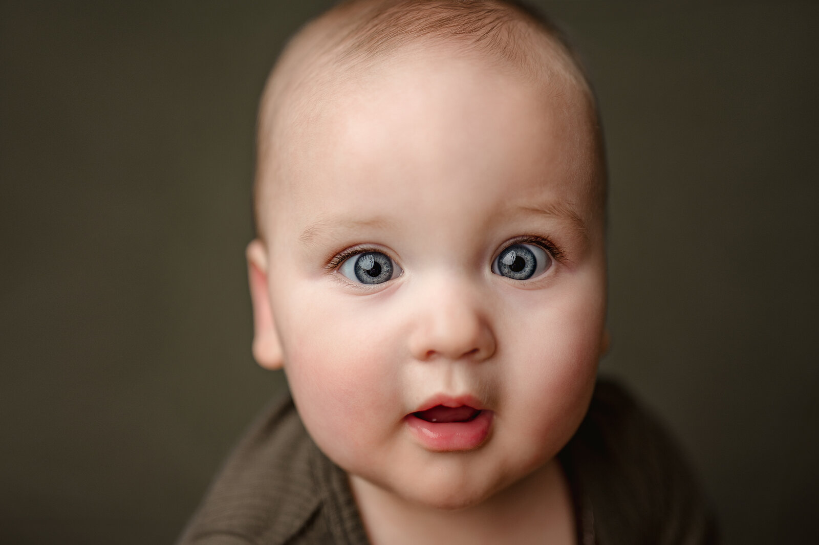 Experience the magic of baby portrait photography with this stunning image of a baby with big blue eyes. Captured in Grand Rapids, this portrait highlights the innocence and wonder of early childhood. Our professional photography services focus on creating beautiful, timeless memories that you and your family will cherish forever. Book your session today to capture the unique expressions and moments of your little one