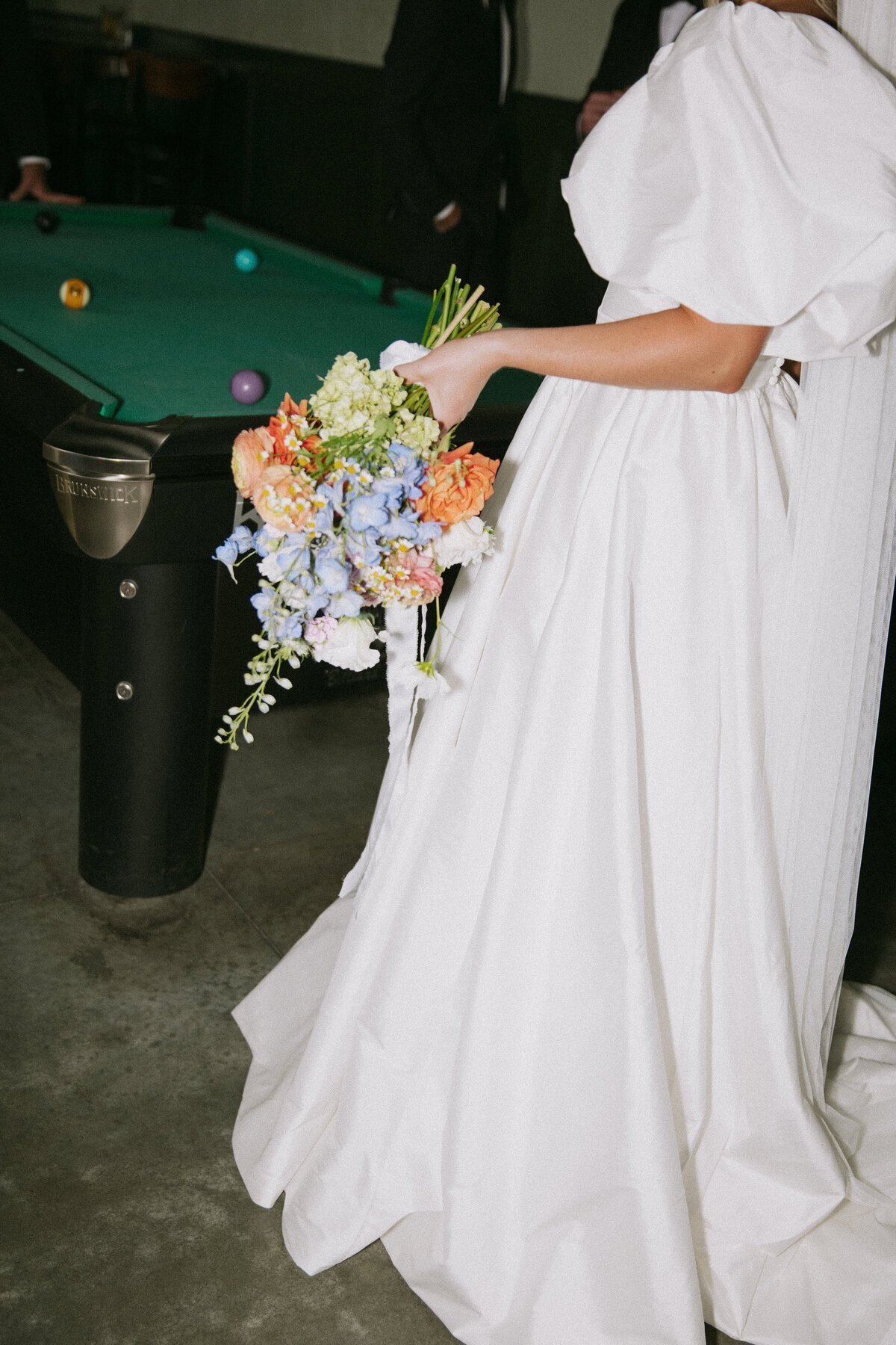 destination wedding photography of bride holding bouquet by pool table