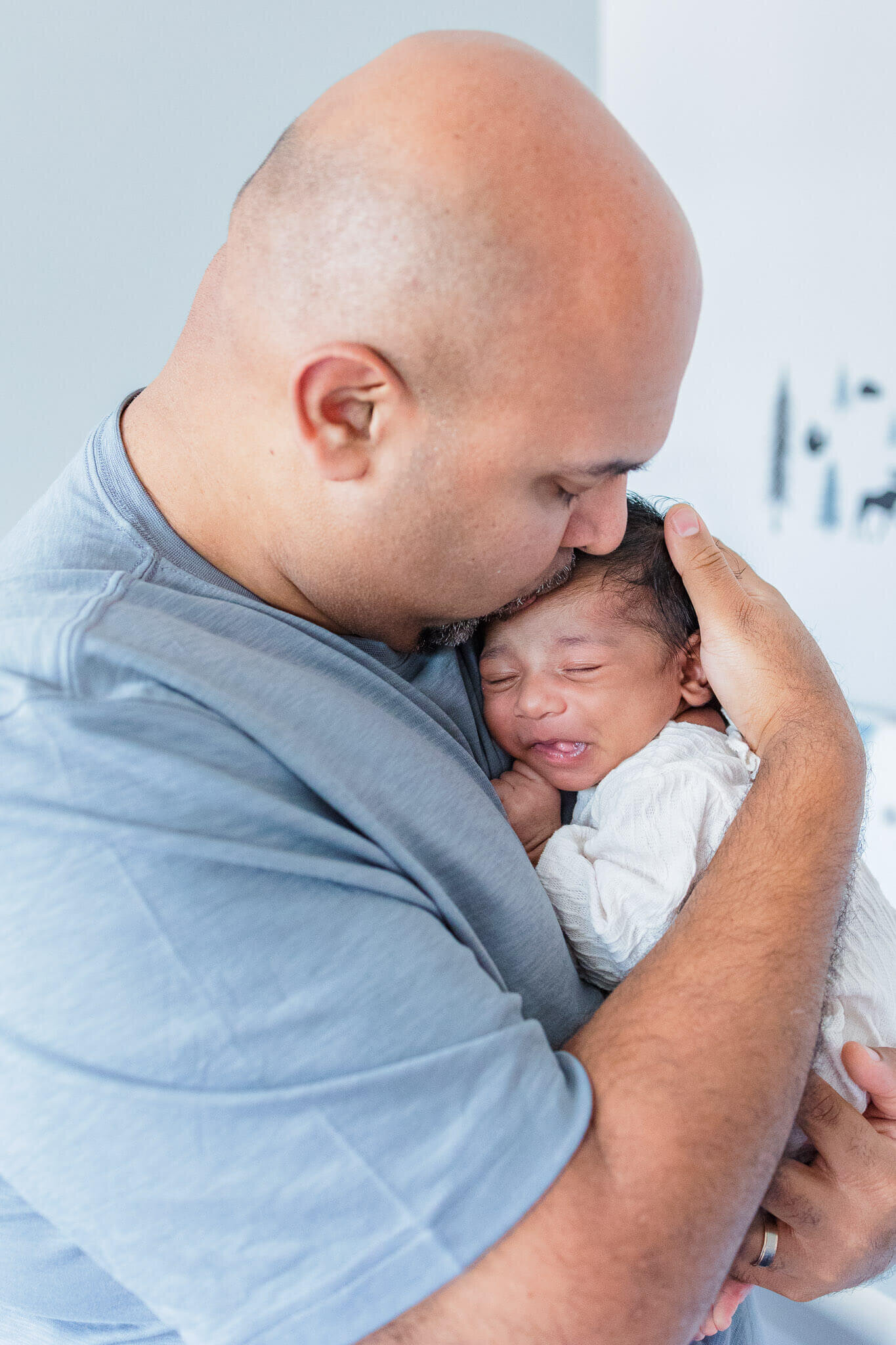 A dad holding and kissing his newborn son.