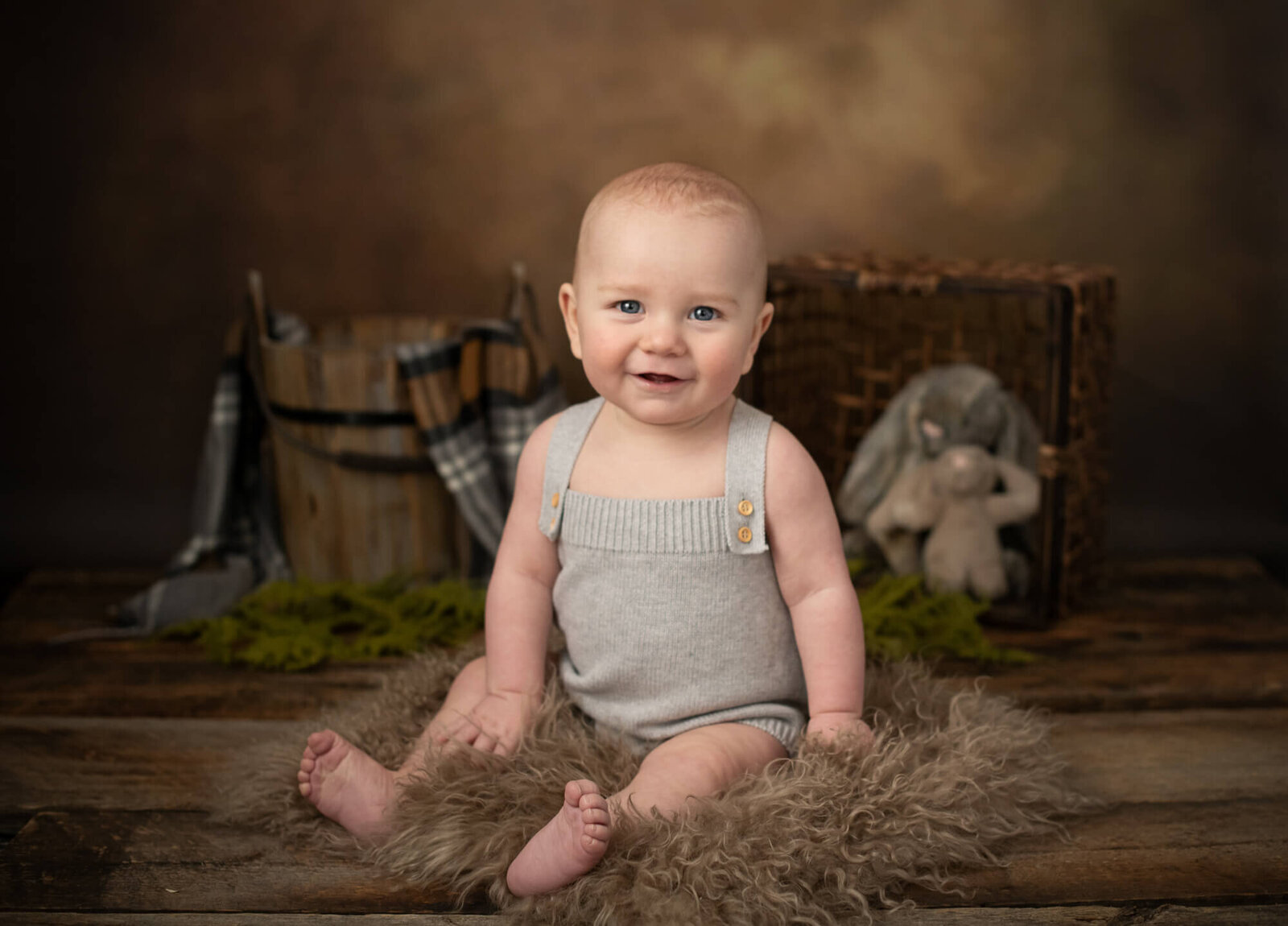 Baby with grey romper and wood  background