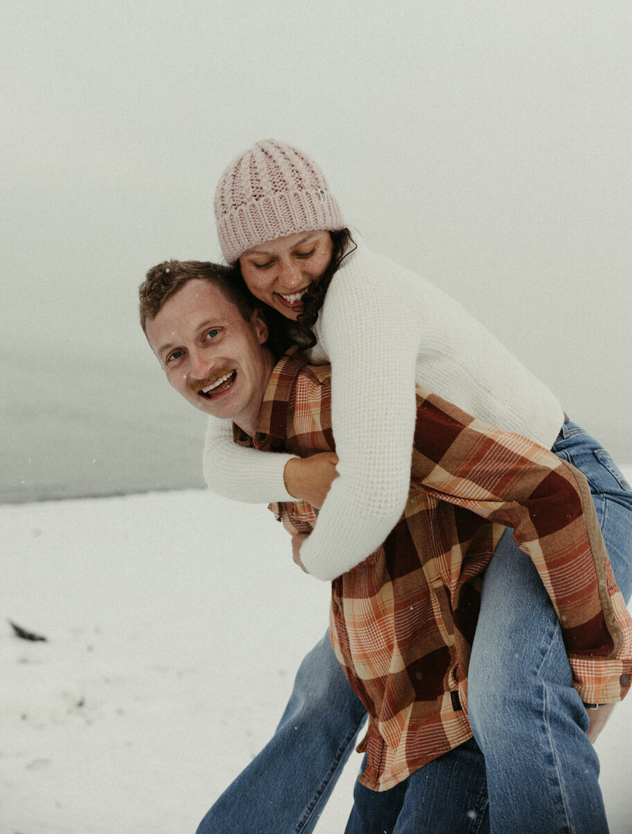 Man giving woman a piggy back ride in the snow