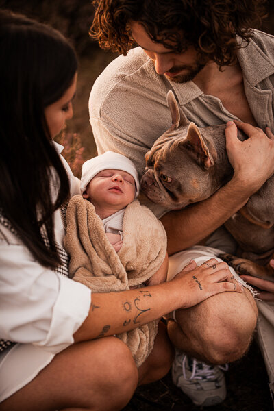 Een newborn fotoshoot in de natuur, omringt door de ouders en trouwe hond