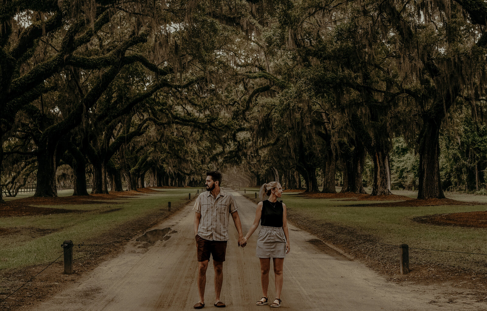 A married couple walking under the trees in Charleston South Carolina.