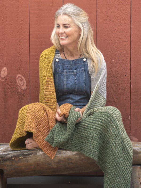 Natural makeup for a model sitting with a blanket in front of a barn