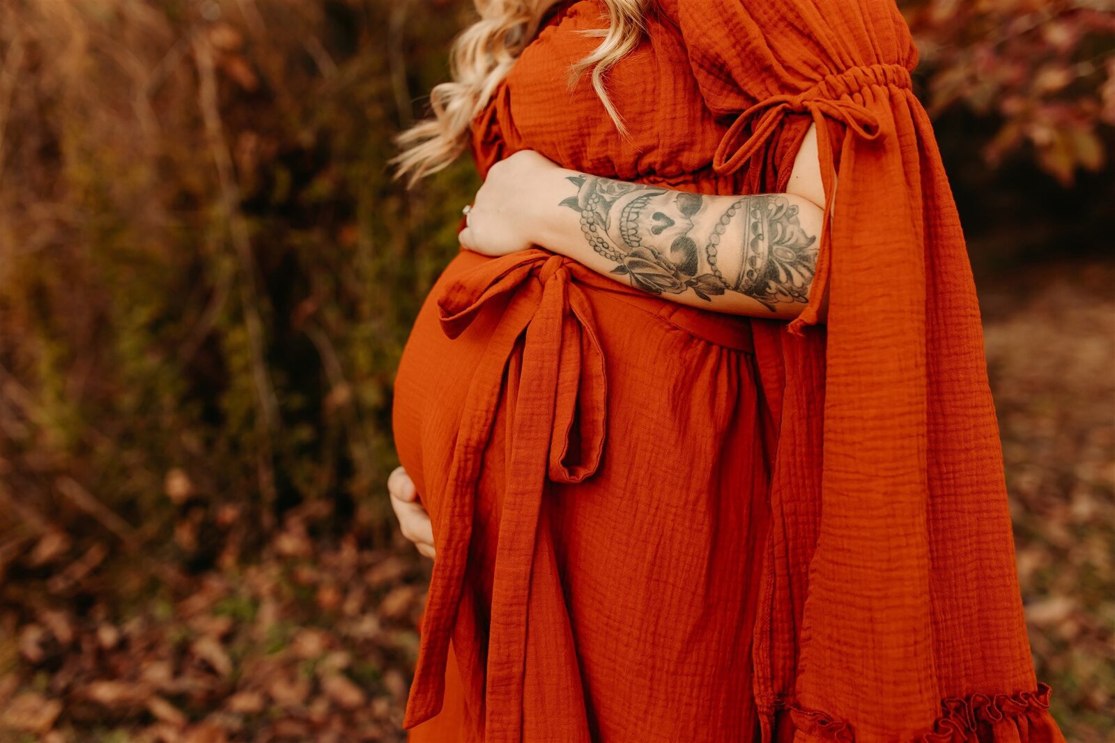 Book your maternity photography session in Cleveland TX - close-up of expectant mother's hand on baby bump in burnt orange gown