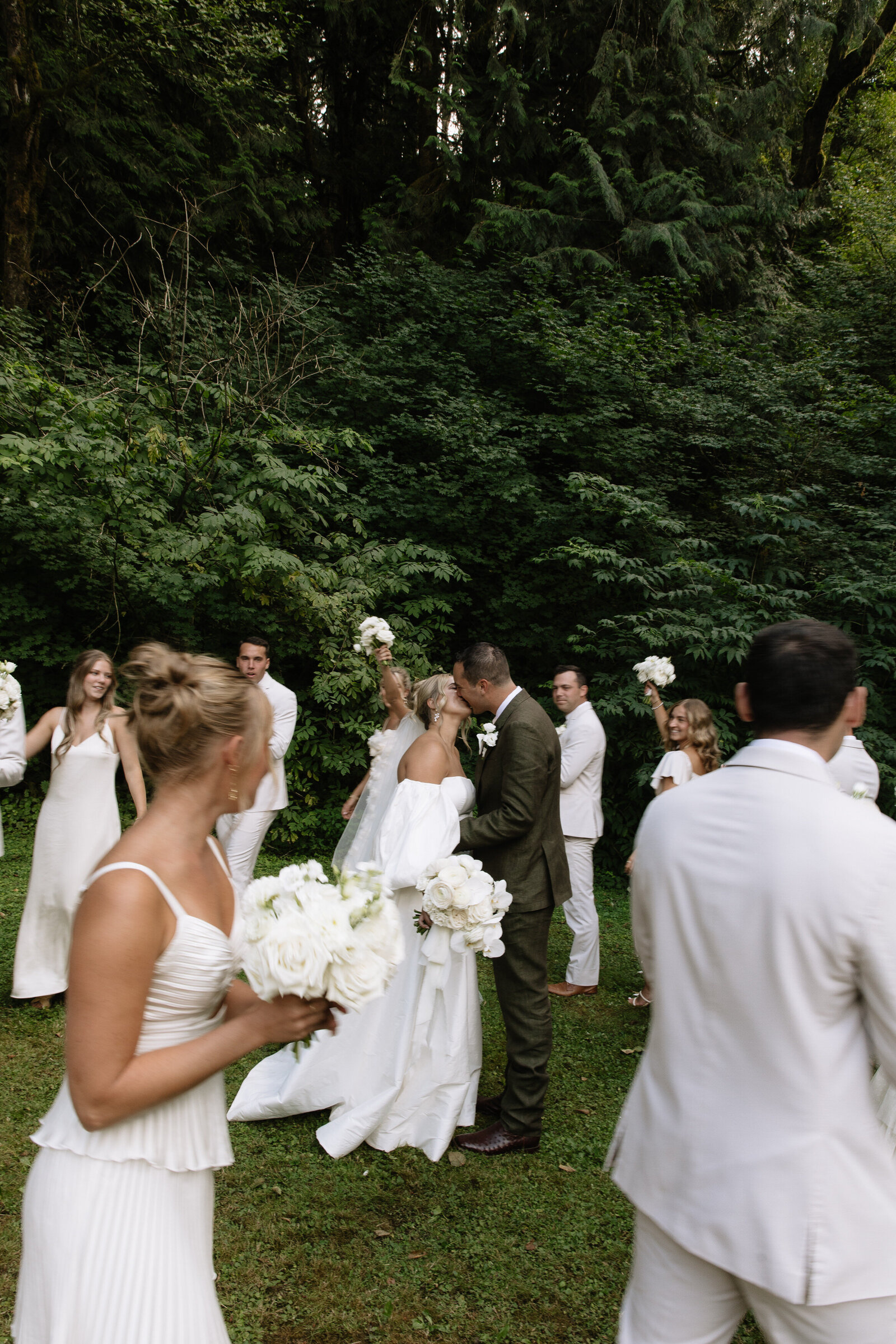 Bridal party celebrating while bride and groom share a kiss after Seattle wedding ceremony