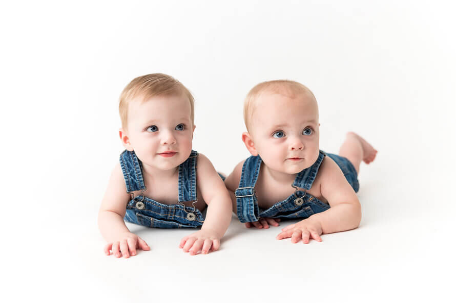 Twin boys smiles for camera in the white studio at Angela Marie Media.