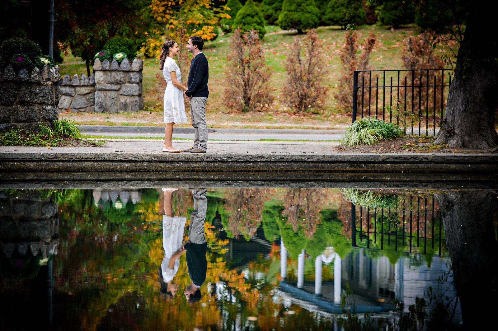 A COUPLE IN A PARK WITH A REFLECTION ON THE WATER