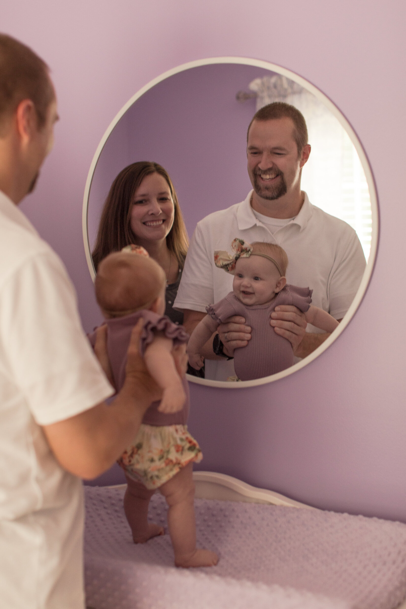 family of three in lilac room looking in a room