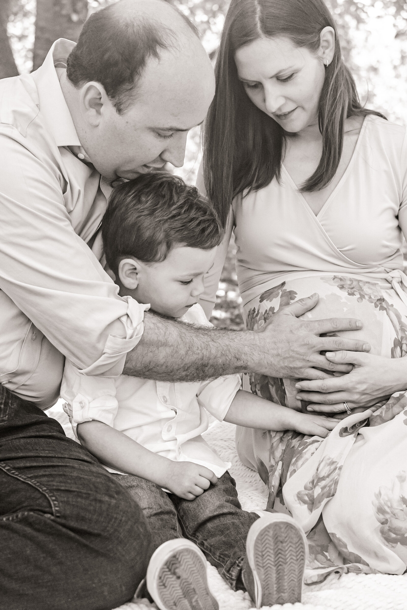 Black and white image of family holding baby bump
