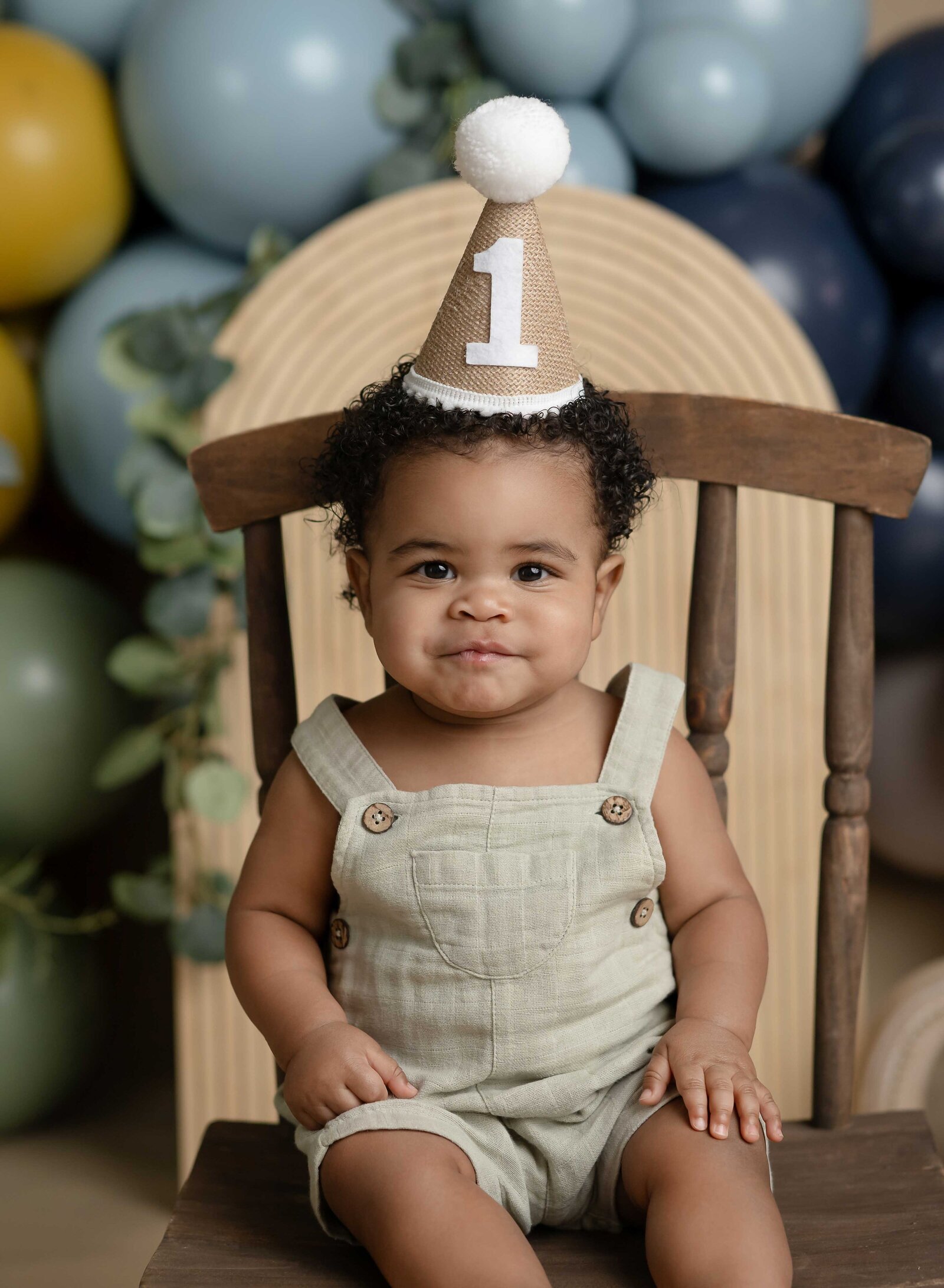 Close up of baby boy with 1st birthday party hat on. Cake smash photo taken by Jenni Nikki Photography in Atlanta, GA.