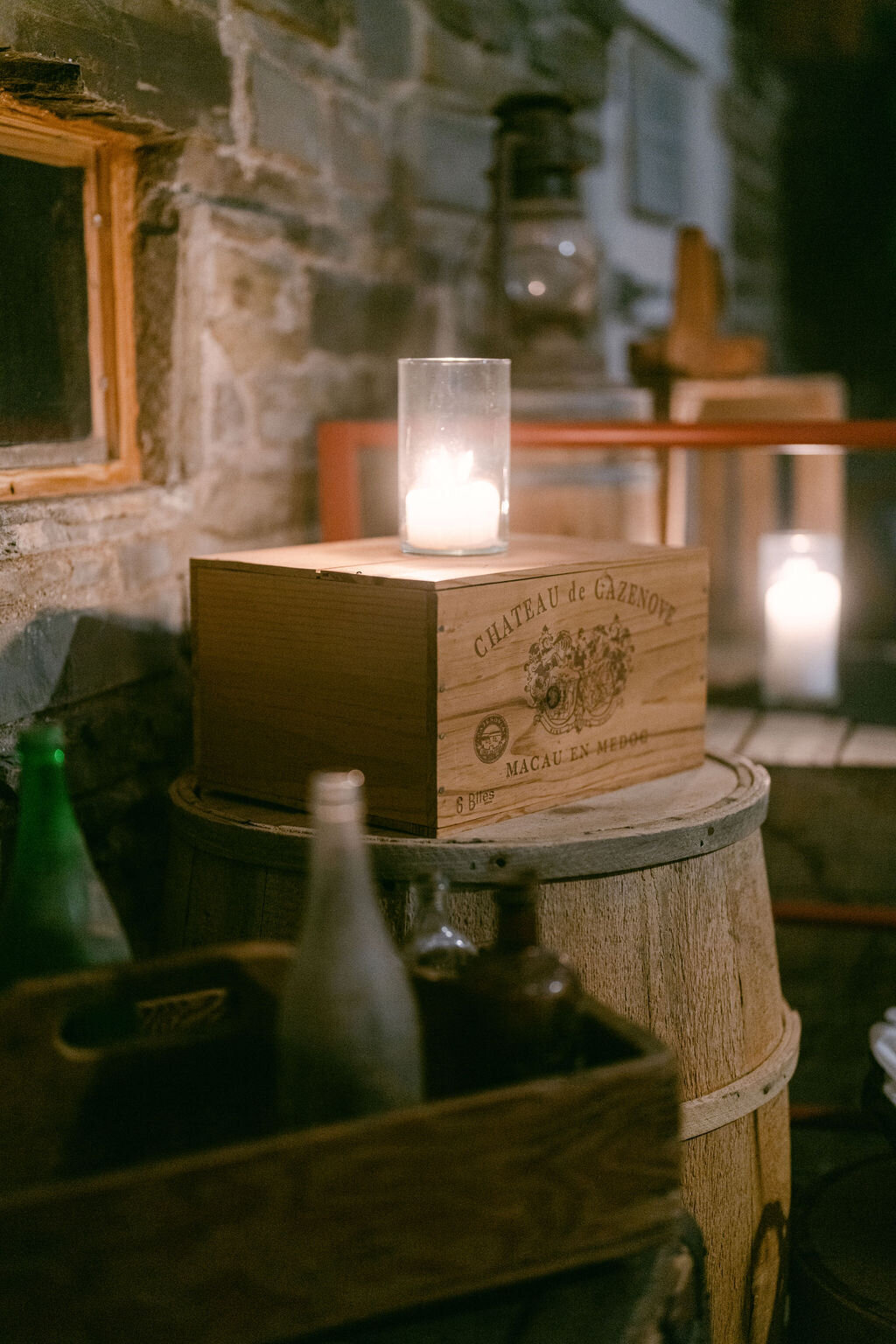stacked vintage crates and bottles with softly glowing candles at Windridge Estate