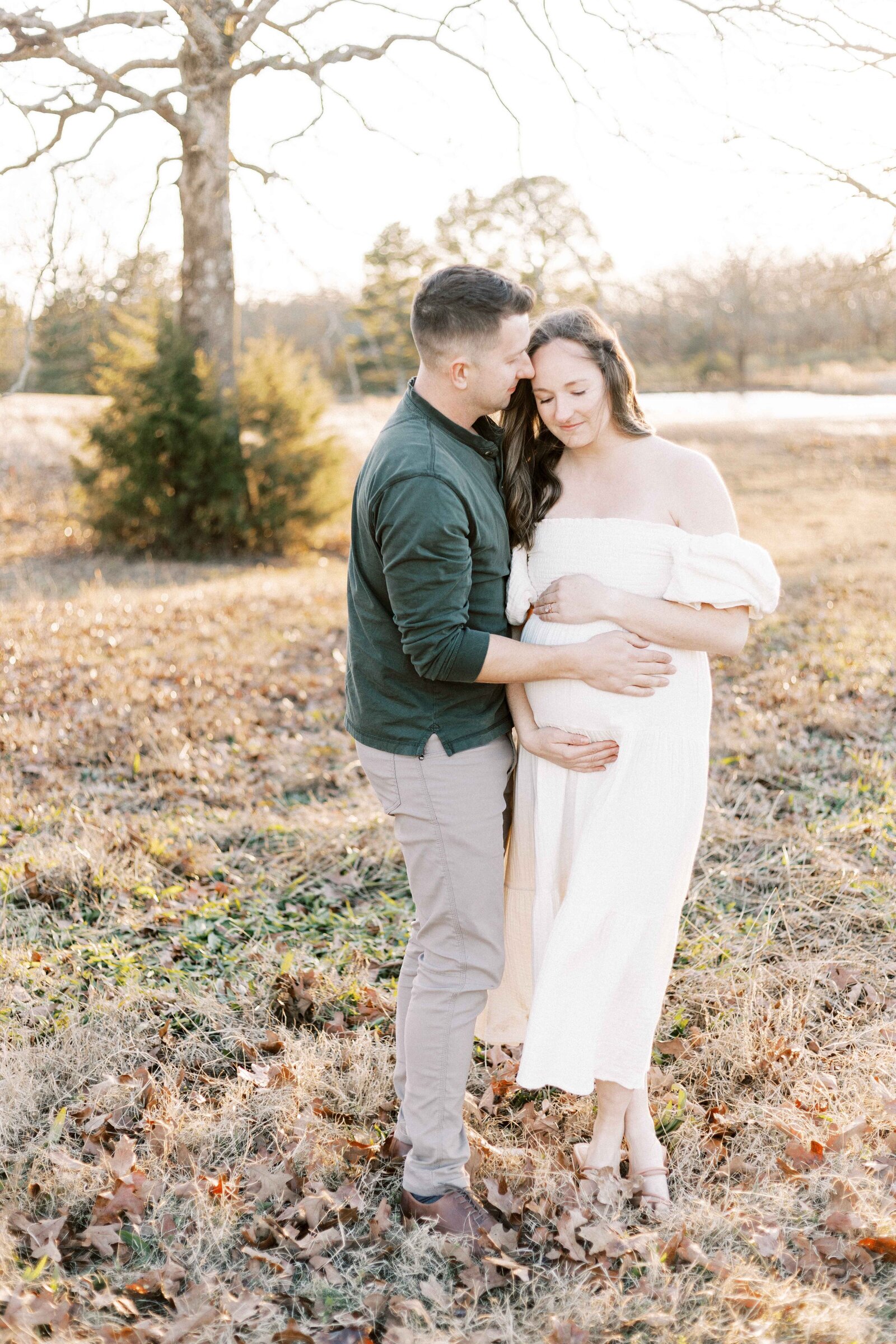 husband and wife holding baby bump in maternity photos in peoria illinois 