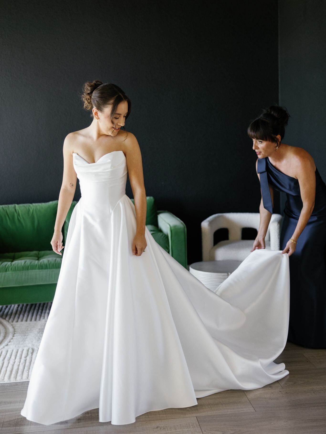 Bride preparing for her wedding day as her mother adjusts her gown.