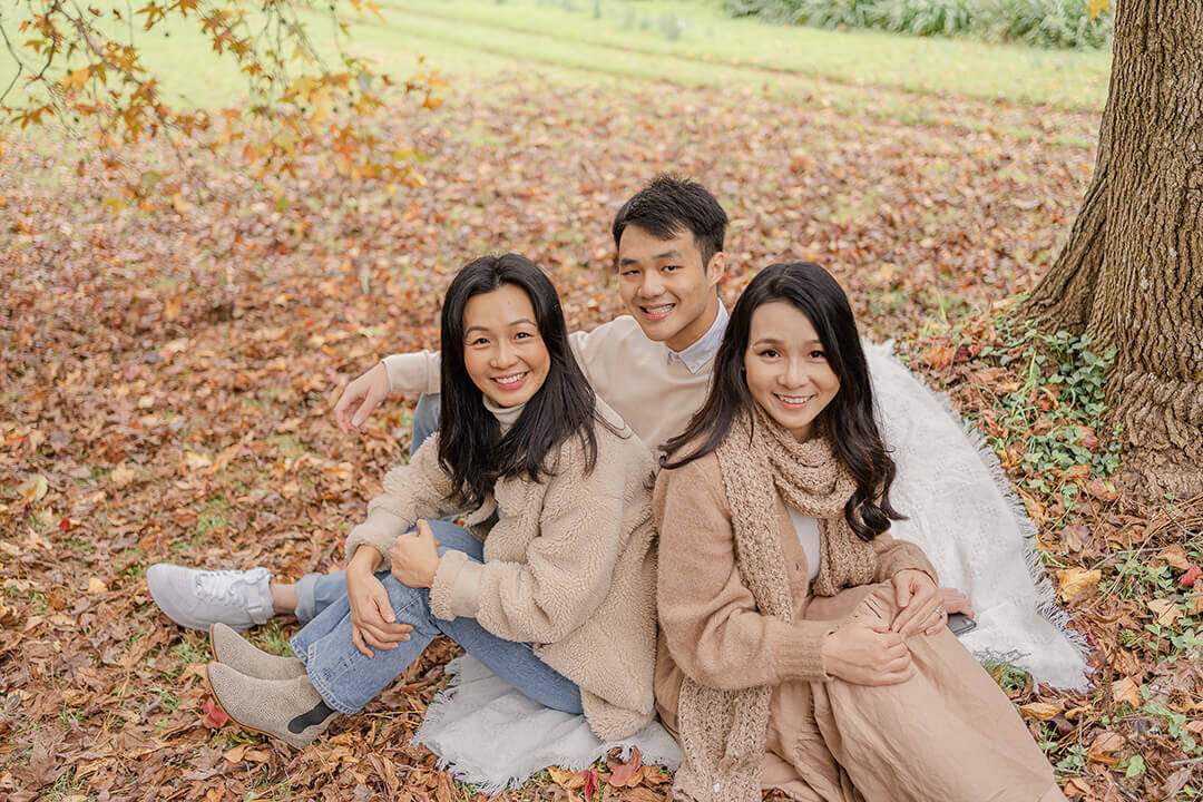 siblings sitting in piles of autumn leaves laughing candid family portrait
