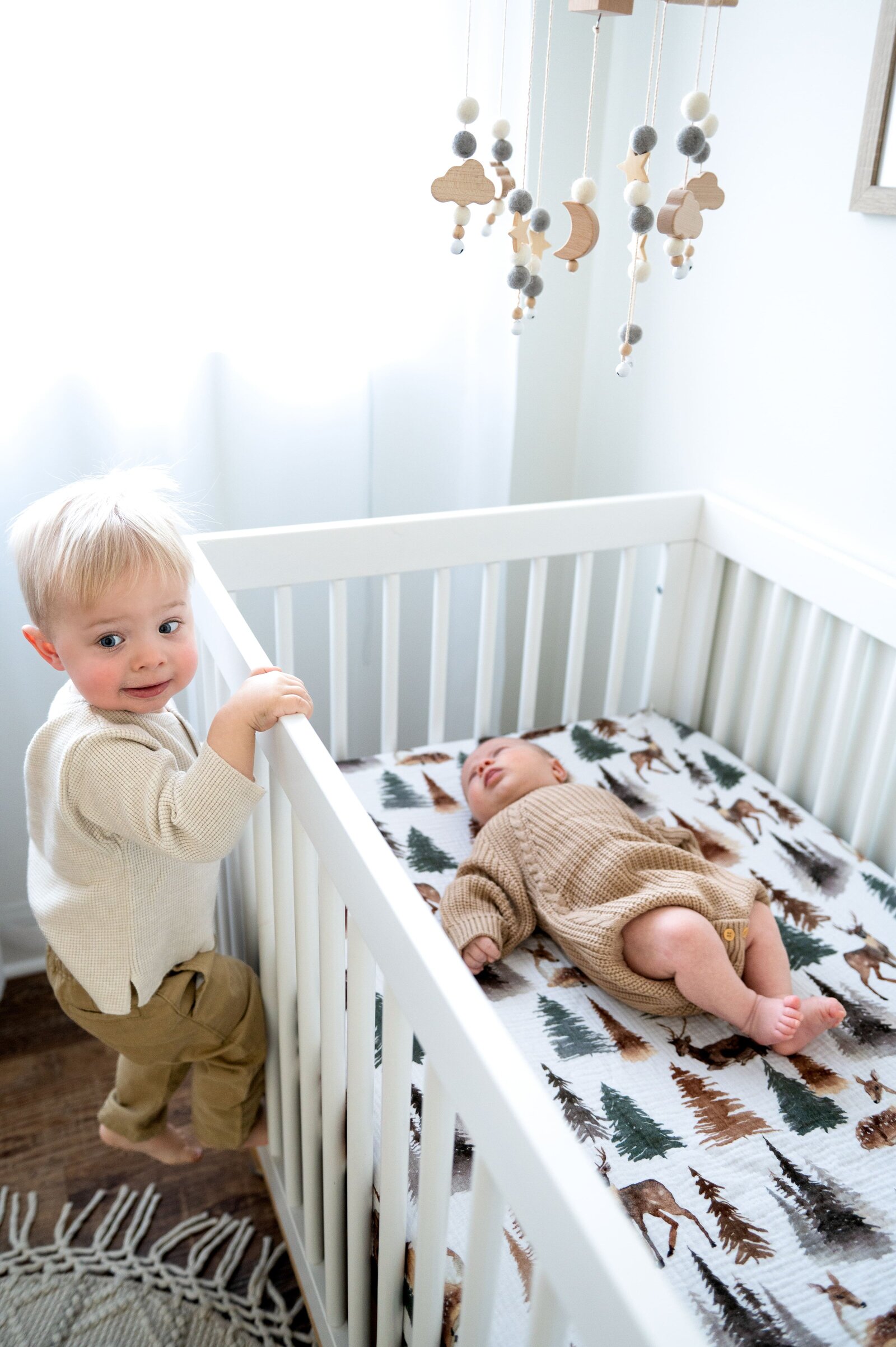 brother looking at his newborn brother in crib